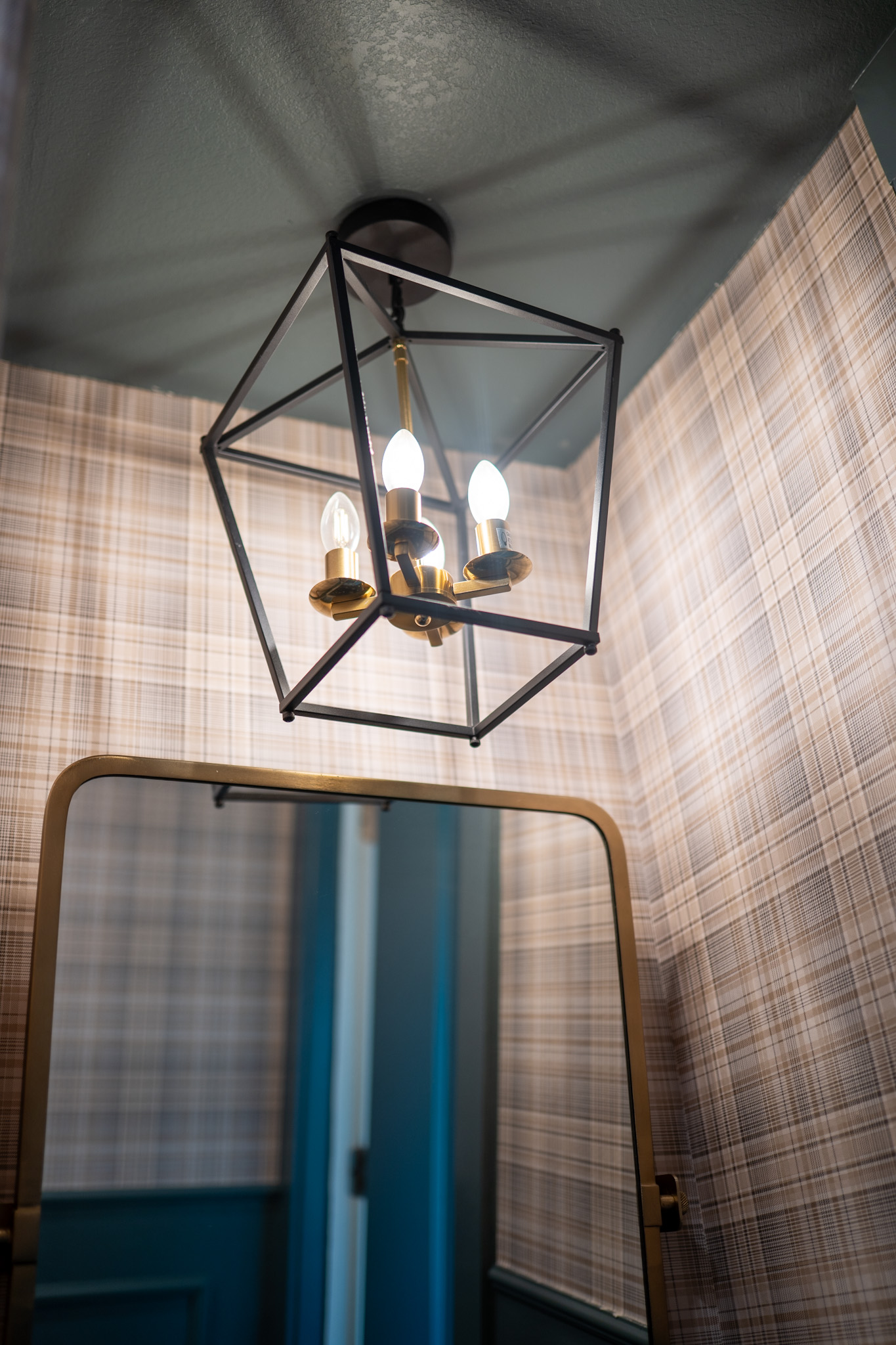 vessel sink, dark blue wall color, black sink, plaid wallpaper, lantern light
